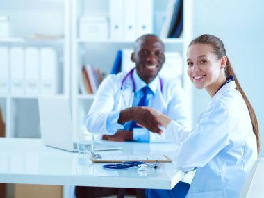 Ofiste tokalaşırken gülümseyen iki genç doktor.