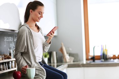 modern mutfakta otururken cep telefonu kullanan kadın