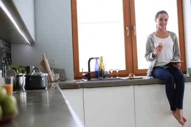 Mutfakta dijital tablet kullanan güzel genç bir kadın.