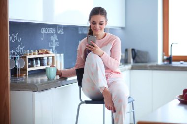 modern mutfakta otururken cep telefonu kullanan kadın