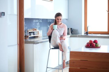 modern mutfakta otururken cep telefonu kullanan kadın