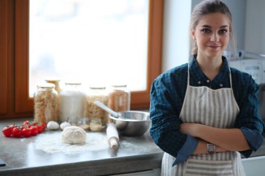 Mutfakta sobanın yanında duran genç bir kadın.