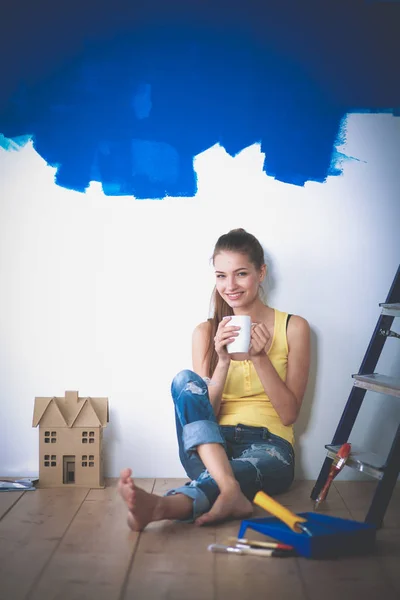 Retrato de pintora sentada en el suelo cerca de la pared después de pintar —  Fotos de Stock