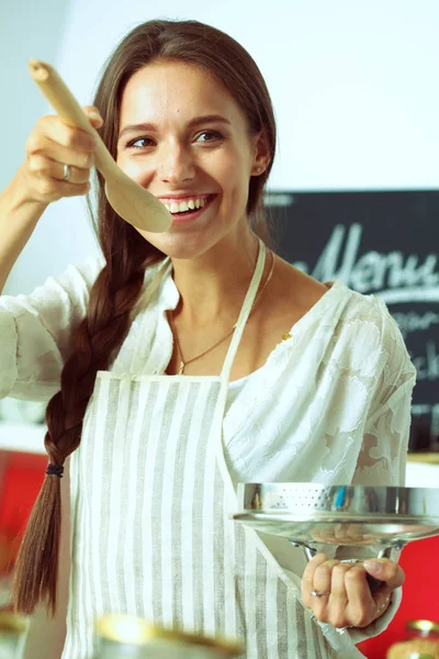 Mujer cocinera en cocina con cuchara de madera —  Fotos de Stock