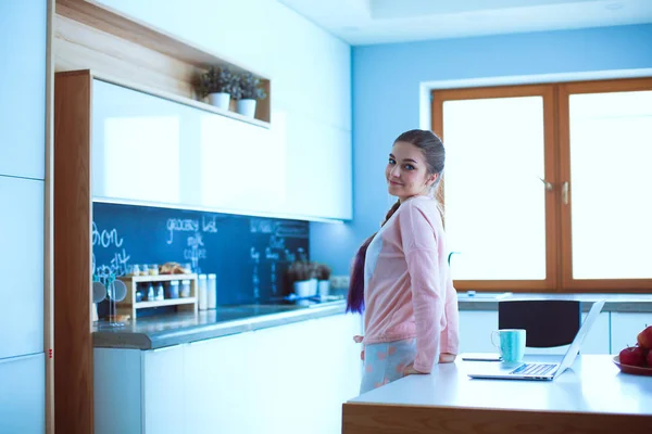 Mulher usando telefone celular de pé na cozinha moderna — Fotografia de Stock