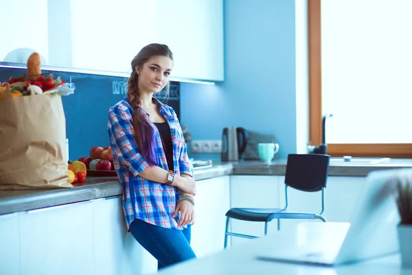 Retrato de mujer joven de pie con los brazos cruzados contra el fondo de la cocina —  Fotos de Stock