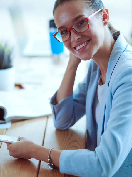 タブレットコンピュータを使って彼女のオフィスに座っているビジネス女性 — ストック写真