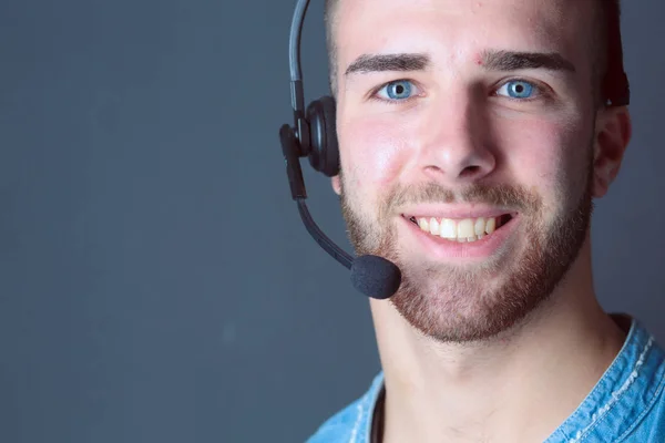 Portret van een jonge man met microfoon staande op een grijze achtergrond — Stockfoto