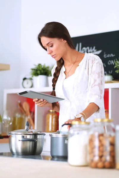 Mujer joven usando una tableta para cocinar en su cocina —  Fotos de Stock