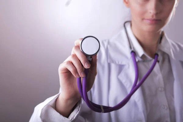 Eine junge Ärztin hört zu und hält ein medizinisches Stethoskop in der Hand — Stockfoto