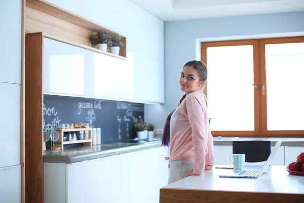 Mulher usando telefone celular de pé na cozinha moderna — Fotografia de Stock