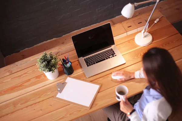 Jeune femme travaillant assise à un bureau — Photo