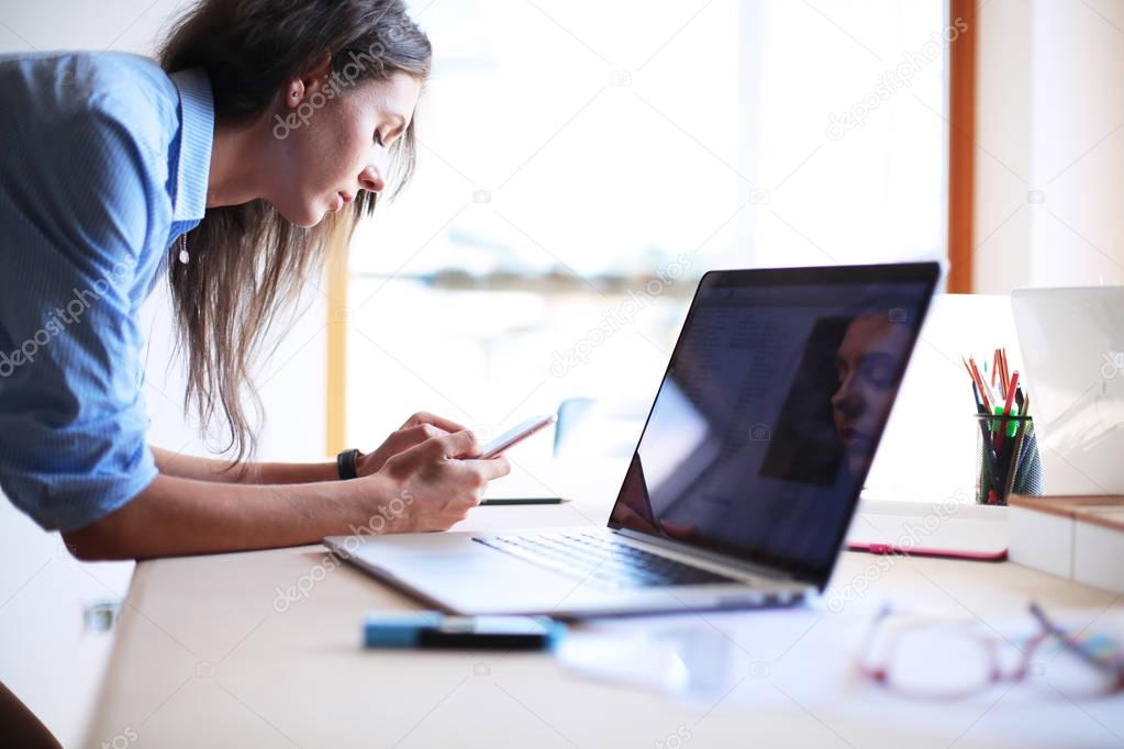 Young woman sitting at office table with laptop