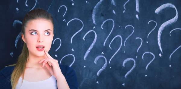 Young girl with question mark on a gray background — Stock Photo, Image