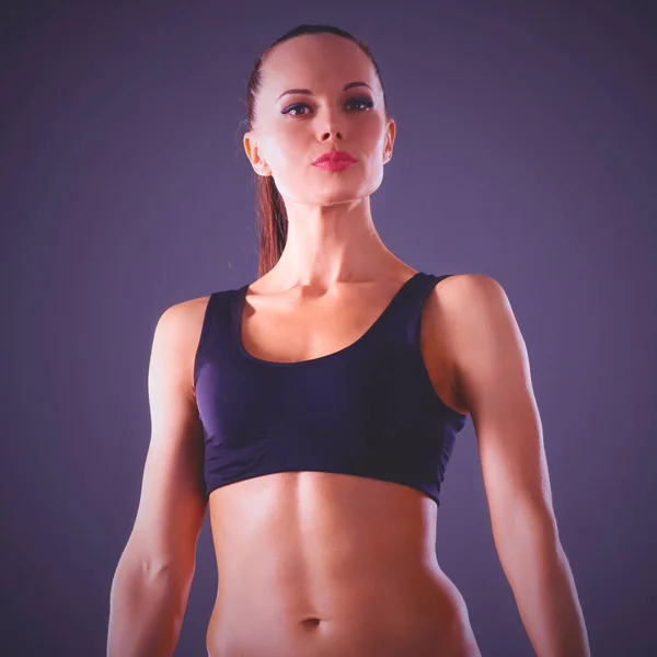 Musculosa joven de pie sobre fondo gris . — Foto de Stock