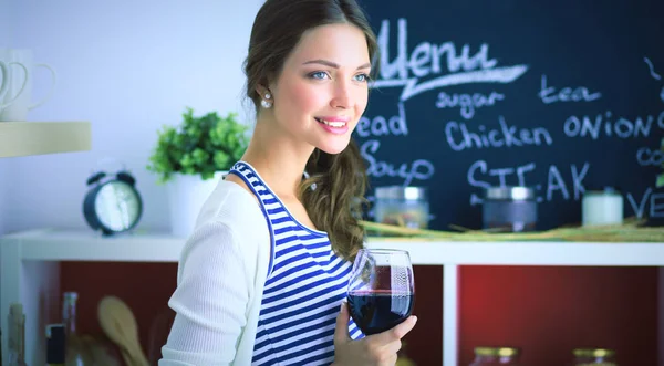 Mooie vrouw die thuis wat wijn drinkt in de keuken . — Stockfoto
