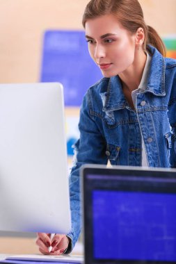 Masanın yanında duran iki genç kadın enstrüman, plan ve dizüstü bilgisayarla