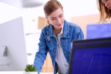 Masanın yanında duran iki genç kadın enstrüman, plan ve dizüstü bilgisayarla