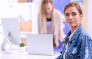 Masanın yanında duran iki genç kadın enstrüman, plan ve dizüstü bilgisayarla