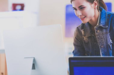 Enstrümanlar, planlar ve dizüstü bilgisayarlarla masanın yanında duran genç bir kadın.