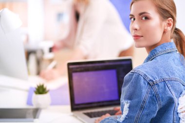 İki genç kadın masada enstrümanlar, planlar ve dizüstü bilgisayarlarla oturuyor.