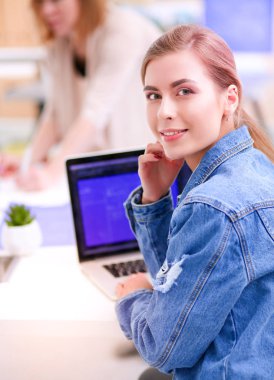 İki genç kadın masada enstrümanlar, planlar ve dizüstü bilgisayarlarla oturuyor.