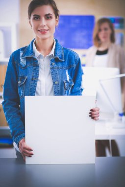 Masanın yanında duran iki genç kadın enstrüman, plan ve dizüstü bilgisayarla