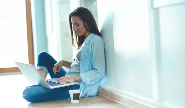 Unga vackra kvinnan hemma sitter på golvet med laptop — Stockfoto