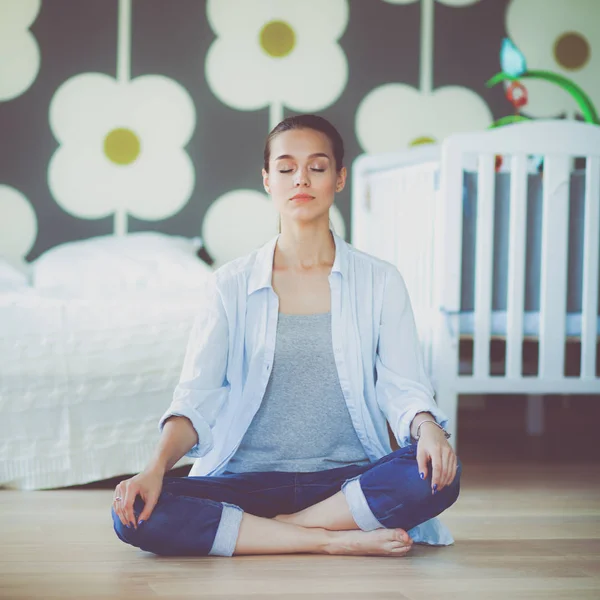 Mujer joven haciendo yoga en casa en la posición de loto — Foto de Stock