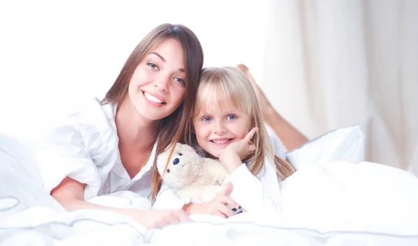 Woman and young girl lying in bed smiling — Stock Photo, Image