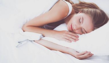 Evdeki yatak odasında uyuyan genç kadın ve çalar saat.