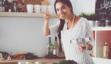 Mutfakta ahşap kaşıkla yemek pişiren kadın