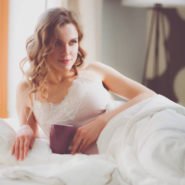 Genç kadın yatakta yatan ise kahve veya çay içme