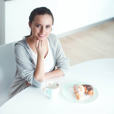 Mutfak masasında tatlı kruvasan ile çay içme kadın