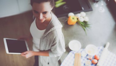 Tablette tarifi takip eden bir kadın evde yemek pişiriyor.