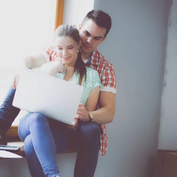 Casal em movimento em casa sentado no peitoril da janela com laptop — Fotografia de Stock