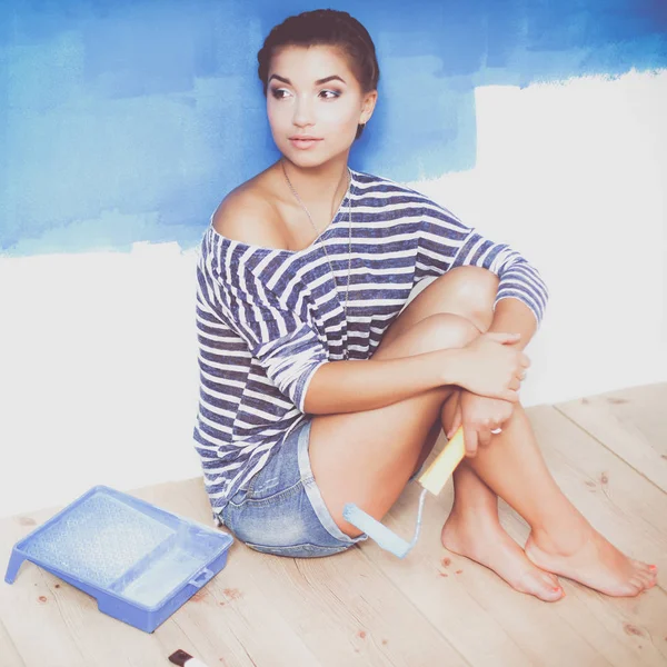 Portrait of female painter sitting on floor near wall after painting — Stock Photo, Image