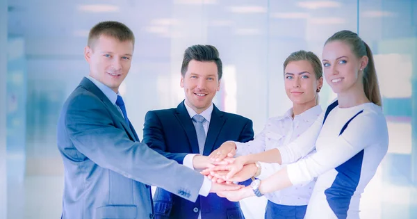 Business team joining hands together standing in office — Stock Photo, Image