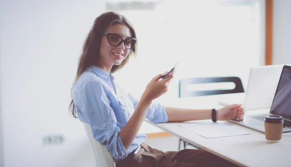 Hermosa joven mujer de negocios sentada en el escritorio de la oficina y hablando por teléfono celular — Foto de Stock