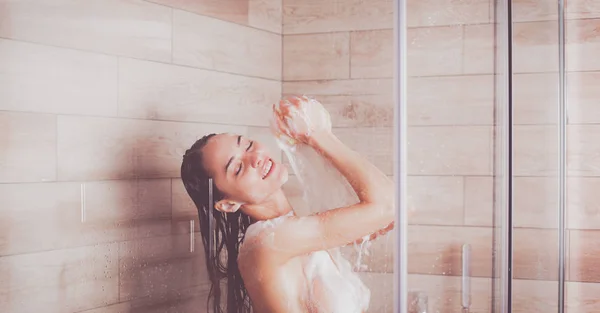 Jeune femme belle sous la douche dans la salle de bain — Photo