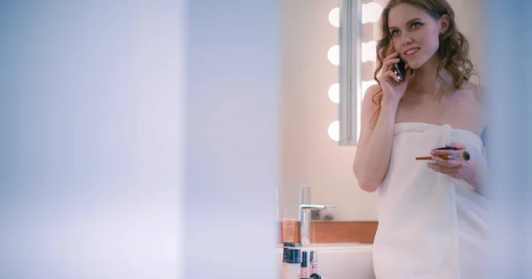 전화와 욕실에 서 있는 젊은 여자 — 스톡 사진