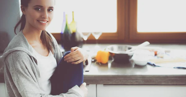 Jonge vrouw zit een tafel in de keuken . — Stockfoto