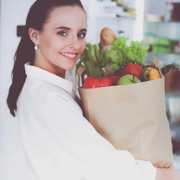 Young woman holding grocery shopping bag with vegetables .Standing in the kitchen — Stock Photo, Image