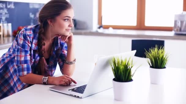 Jonge vrouw staat in de keuken met behulp van laptop — Stockvideo