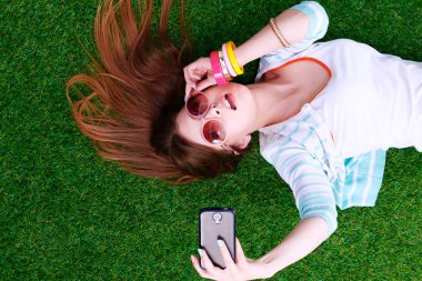 Çim üzerinde yalan ve bir selfie yapma gülümseyen genç kadın