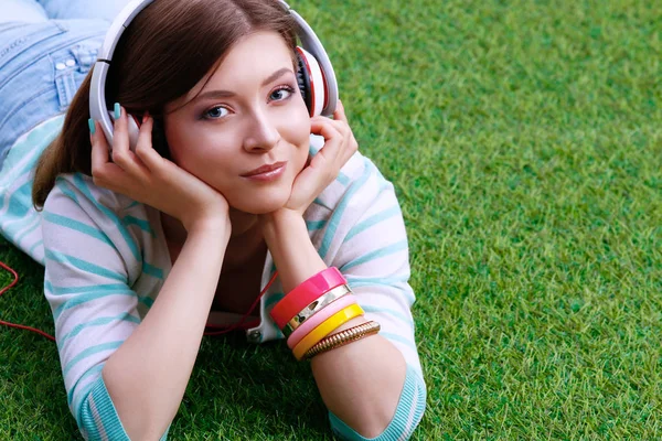 Mujer escuchando la música tumbada sobre hierba verde —  Fotos de Stock