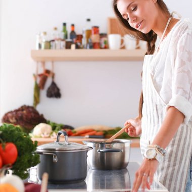 Mutfakta yemek yapmak için tablet bilgisayar kullanan genç bir kadın. .