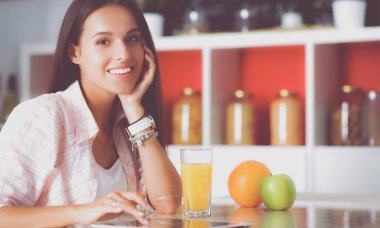 Mutfakta yemek yapmak için tablet bilgisayar kullanan genç bir kadın. .