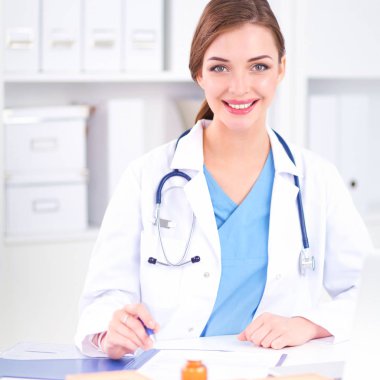 Güzel, genç, gülümseyen bayan doktor masada oturuyor ve...