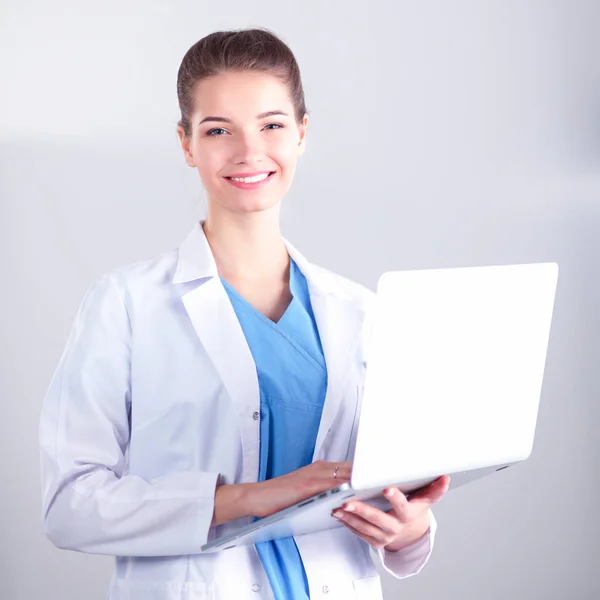 Красивая женщина врач или медсестра держит ноутбук компьютер изолирован на белом фоне — стоковое фото